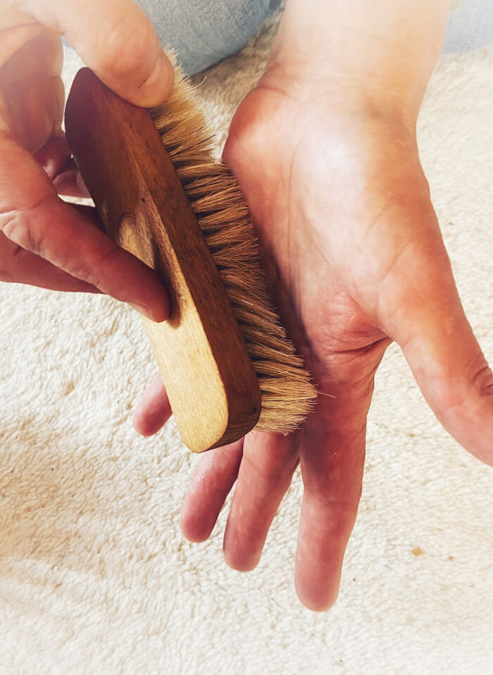 Eine weiche Bürste, mit der über eine Hand gestreichelt wird.